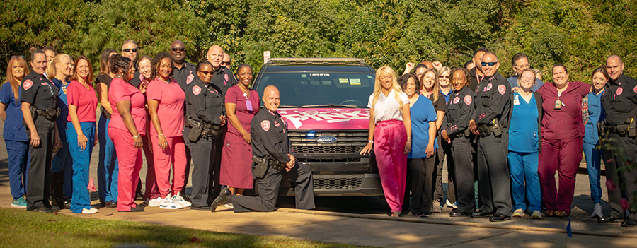 Police and medical personnel posing with a pink TPD car