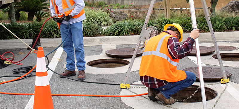 a crew inspecting a storm sewer drain